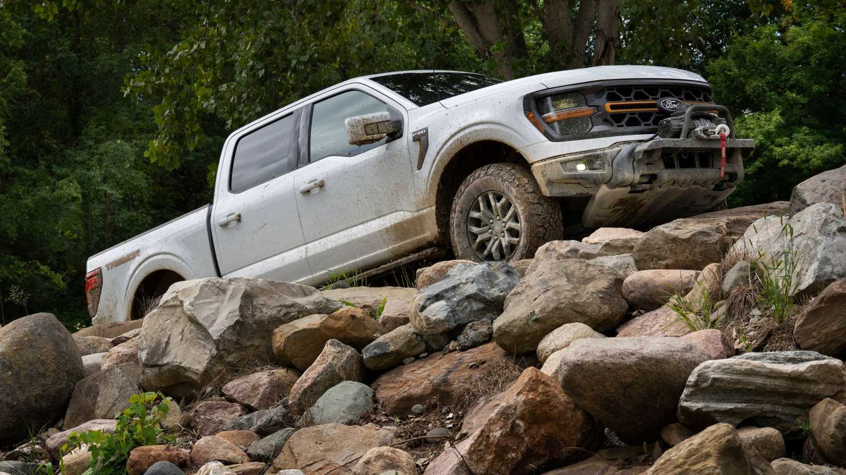 Dynamic front 3/4 shot of a wqhite 2024 Ford F-150 Tremor off-roading.