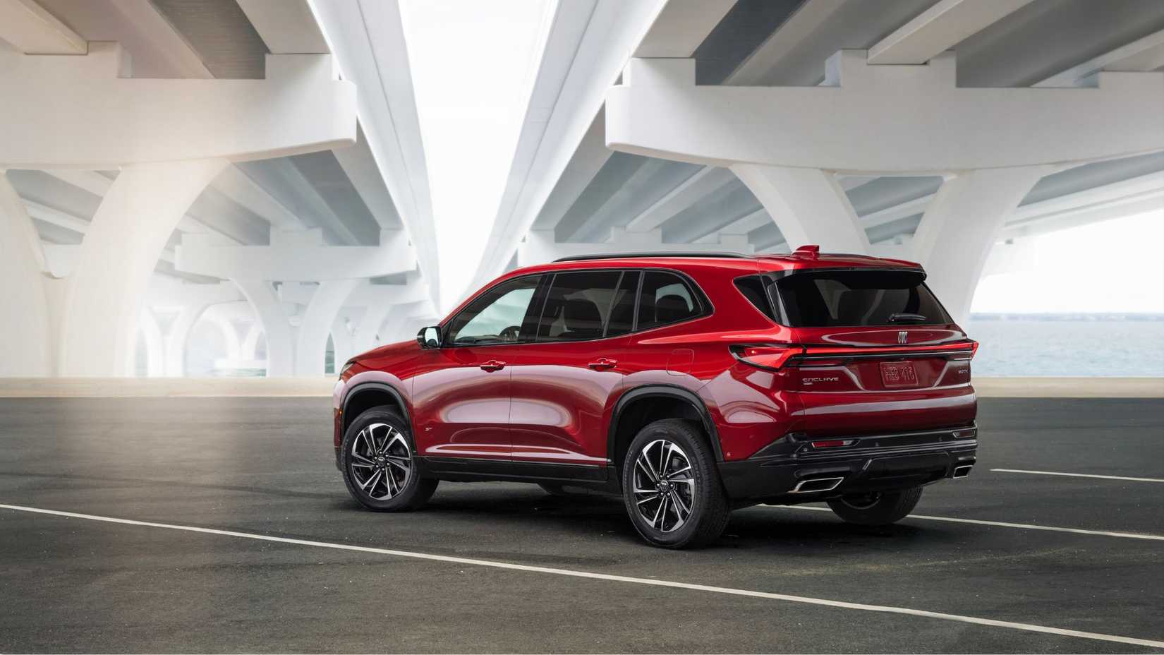 Static rear 3/4 shot of a red 2025 Buick Enclave Sport Touring parked underneath a bridge.