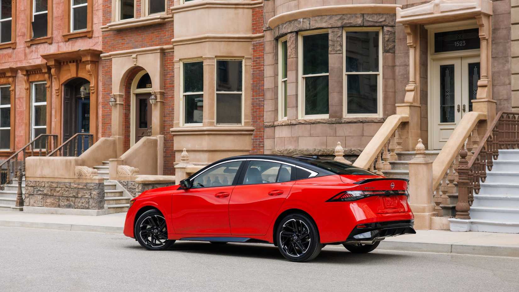 Static rear 3/4 shot of a red 2026 Nissan Sentra parked in a city.