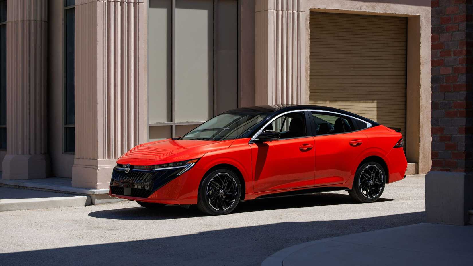 Static front 3/4 shot of a red 2026 Nissan Sentra parked in a city.