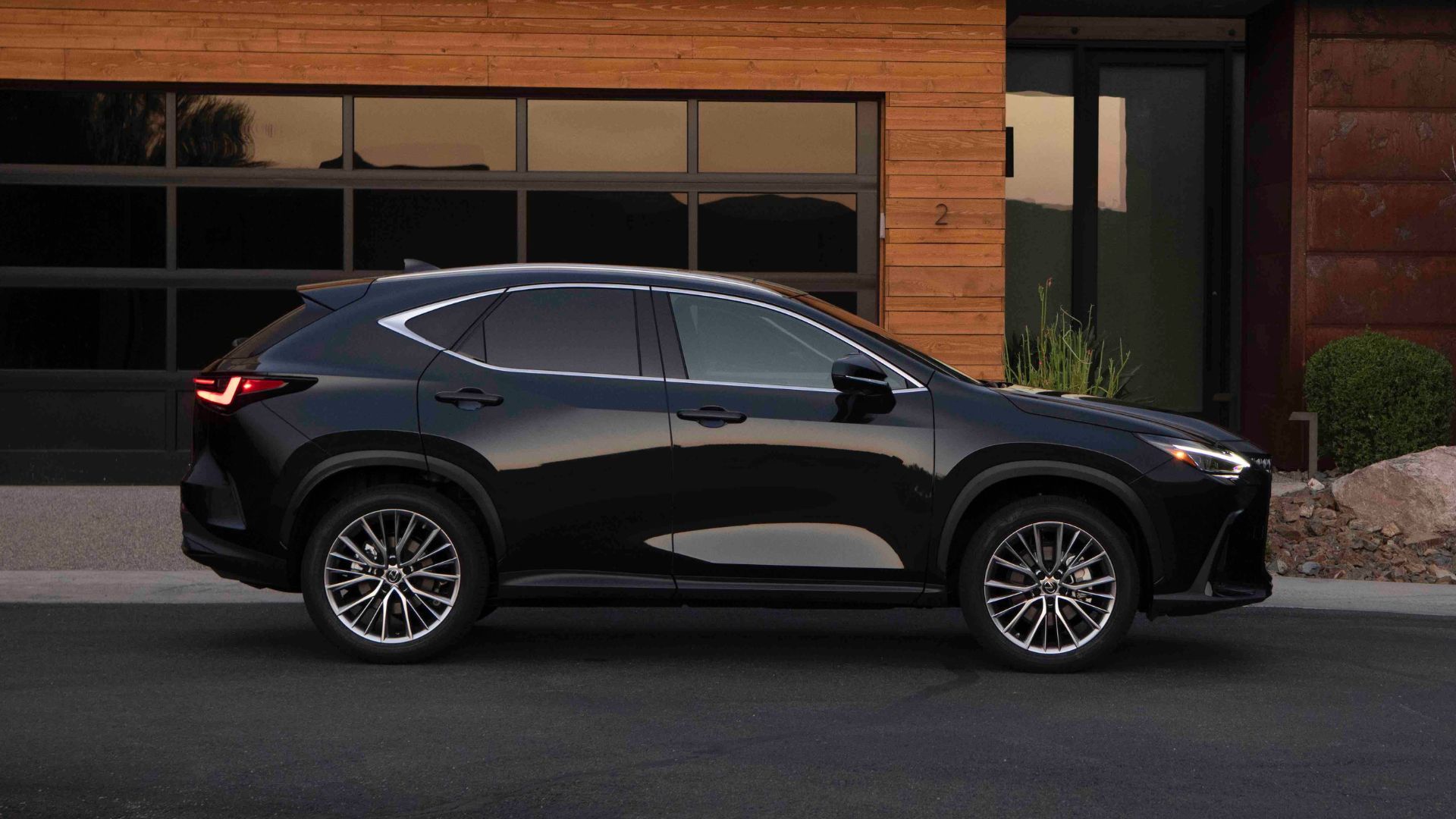 Static side profile photo of a black 2026 Lexus NX 350 parked outside a house.
