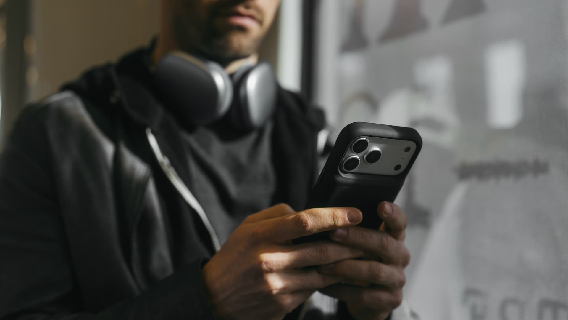 A person using a Juice Back on an iPhone with headphones on