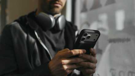A person using a Juice Back on an iPhone with headphones on