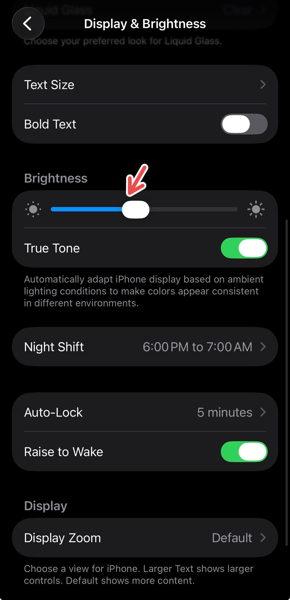 An iPhone screenshot showing a red arrowing pointing to the brightness bar in Display & Brightness.