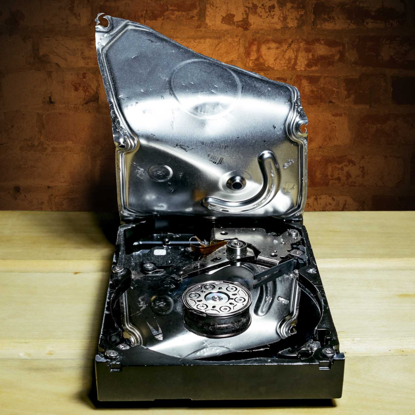 Uma captura de tela de um disco rígido quebrado com a parte superior do HDD aberta, apoiada em uma bancada.