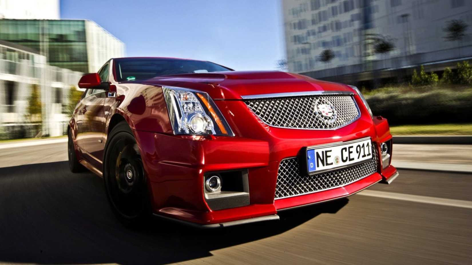 Dynamic front 3/4 shot of a red 2011 Cadillac CTS-V Wagon driving in a city.