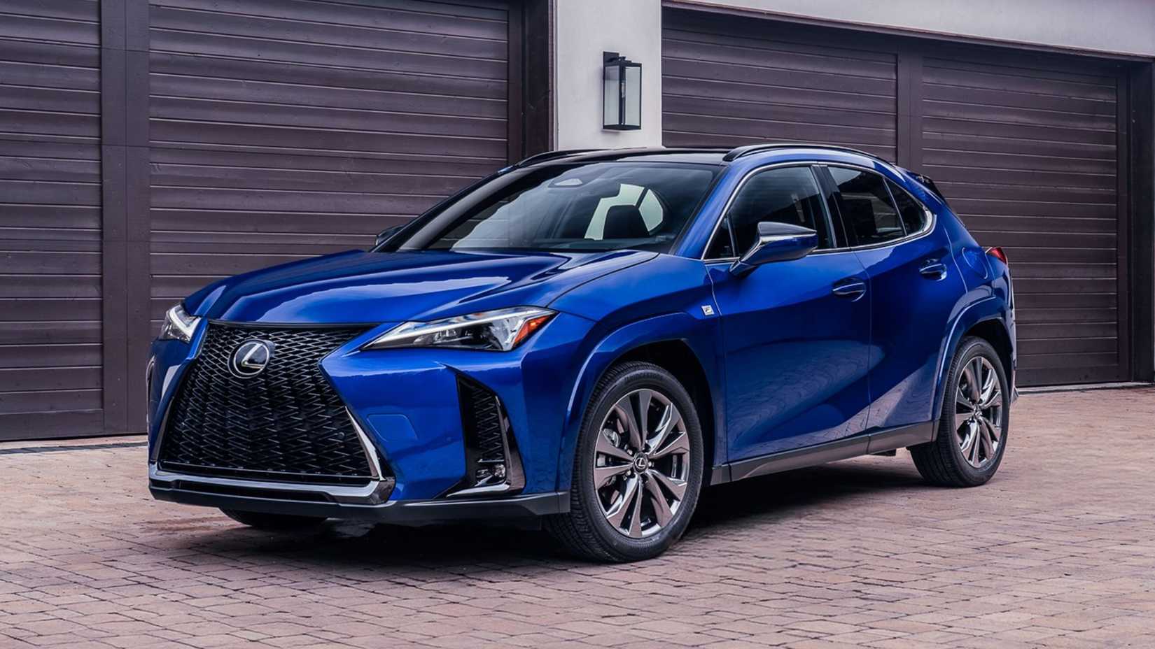 Static front 3/4 shot of a blue 2026 Lexus UX Hybrid F-SPORT parked outside of a garage.