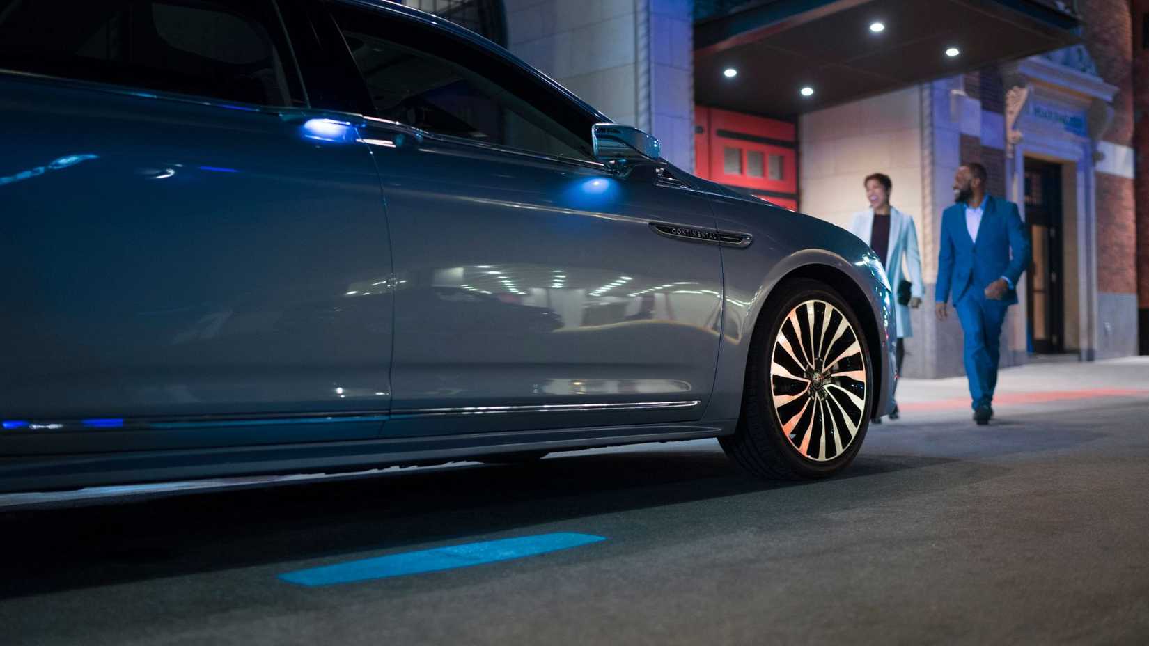 Close-up shot of the side of a Lincoln Continental Coach Doors with its puddle lights glowing at night.