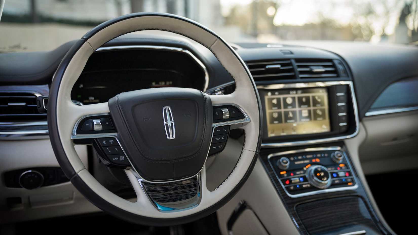 Close-up shot of the steering wheel and infotainment screen in a Lincoln Continental Coach Doors.