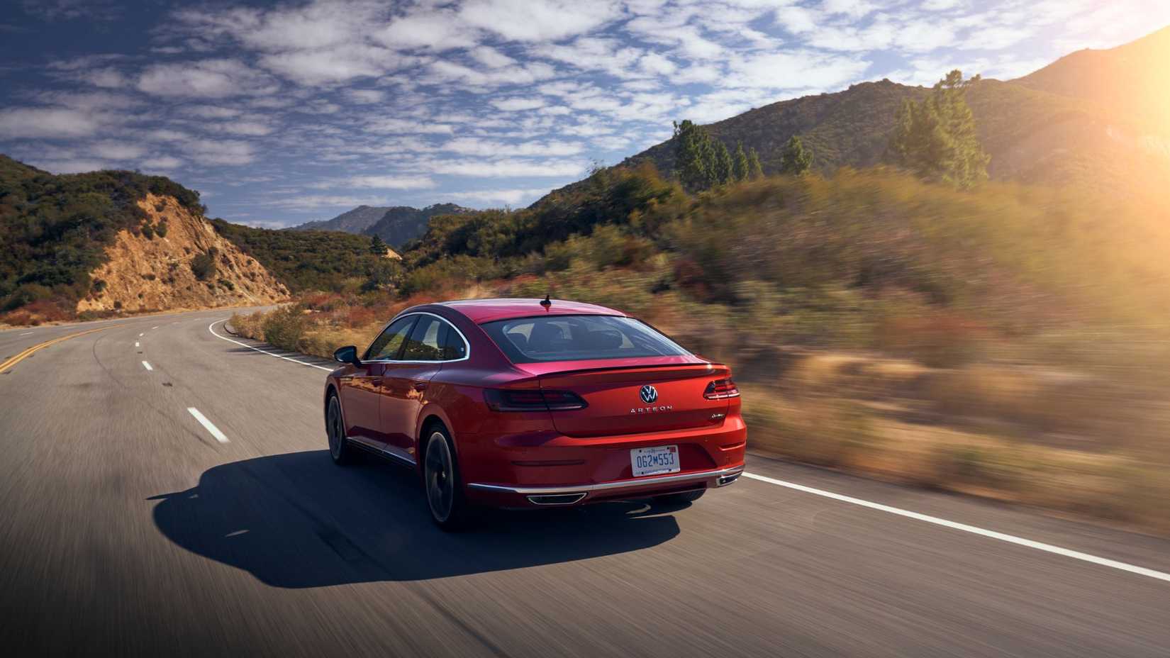 Dynamic rear 3/4 shot of a red 2021 Volkswagen Arteon driving on a country road.
