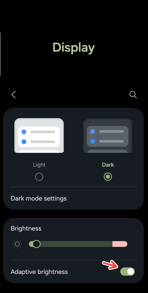 A screenshot on an Android device showing a red arrow pointing to the Adaptive Brightness setting.