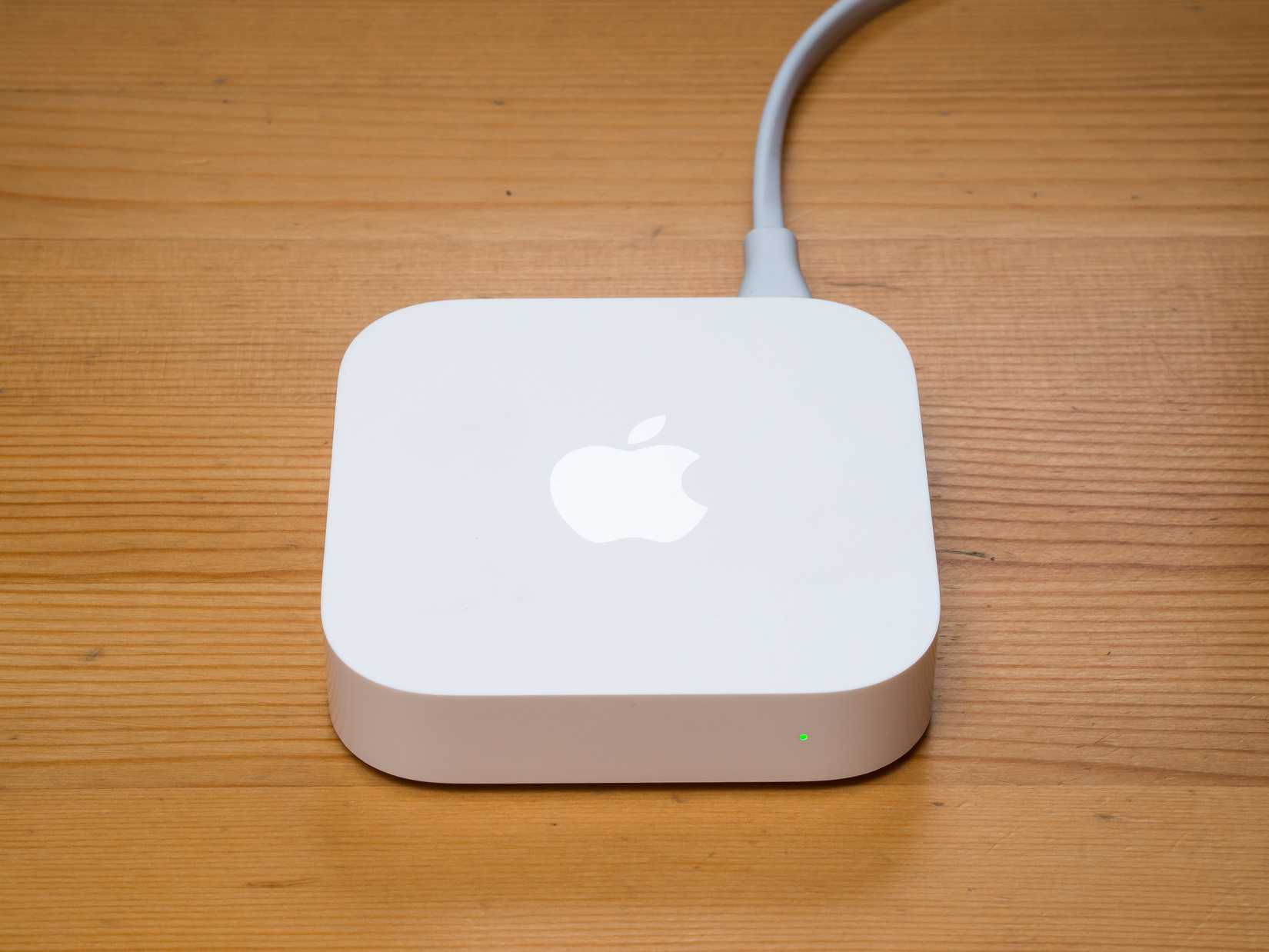 An Apple AirPort Express sitting on a wooden desk.