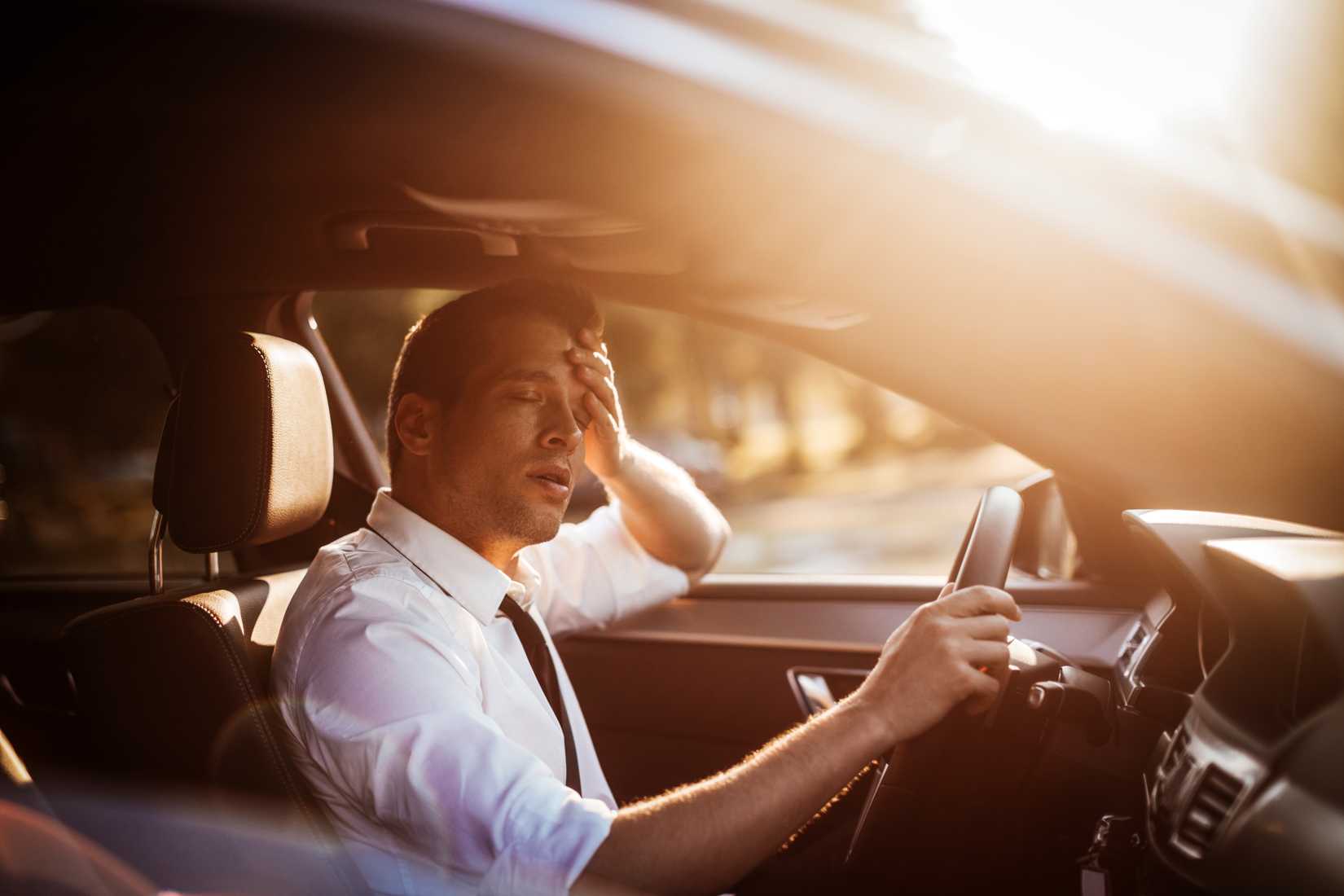 A businessman is tired while driving the car to work.