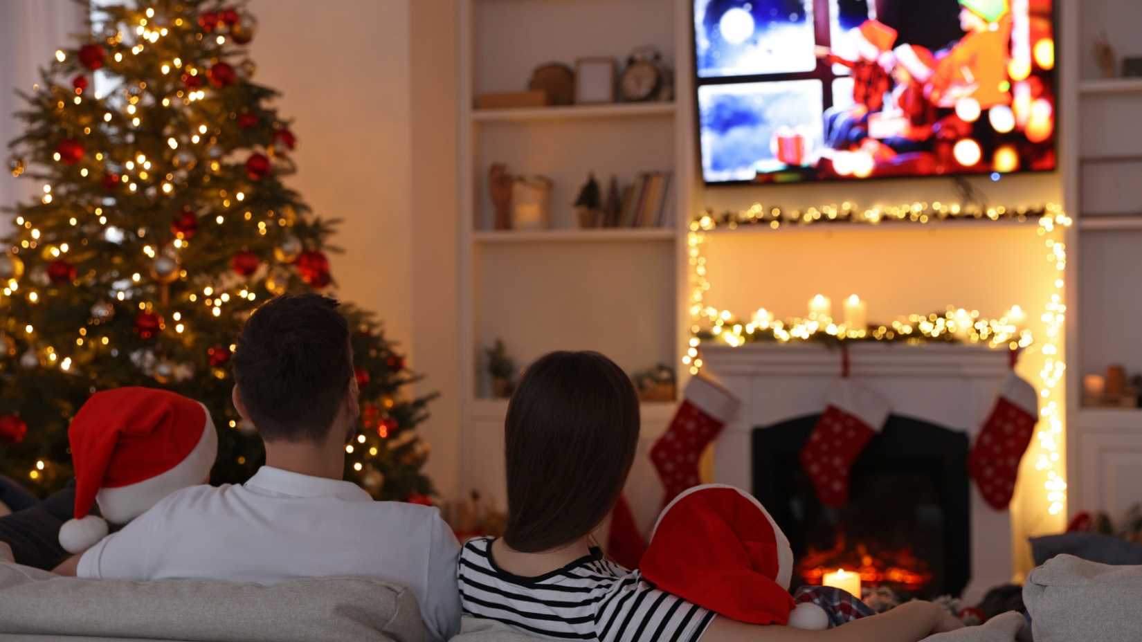 A family watches Christmas-related content on a television.