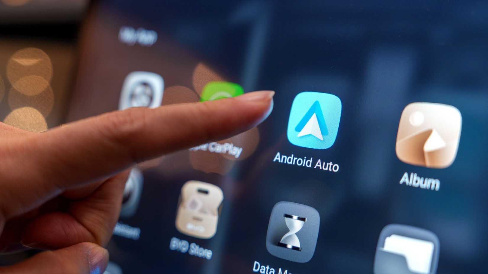Close-up of a user interacting with the Android Auto pairing interface on the digital display inside a BYD electric car at an auto show in Penang.