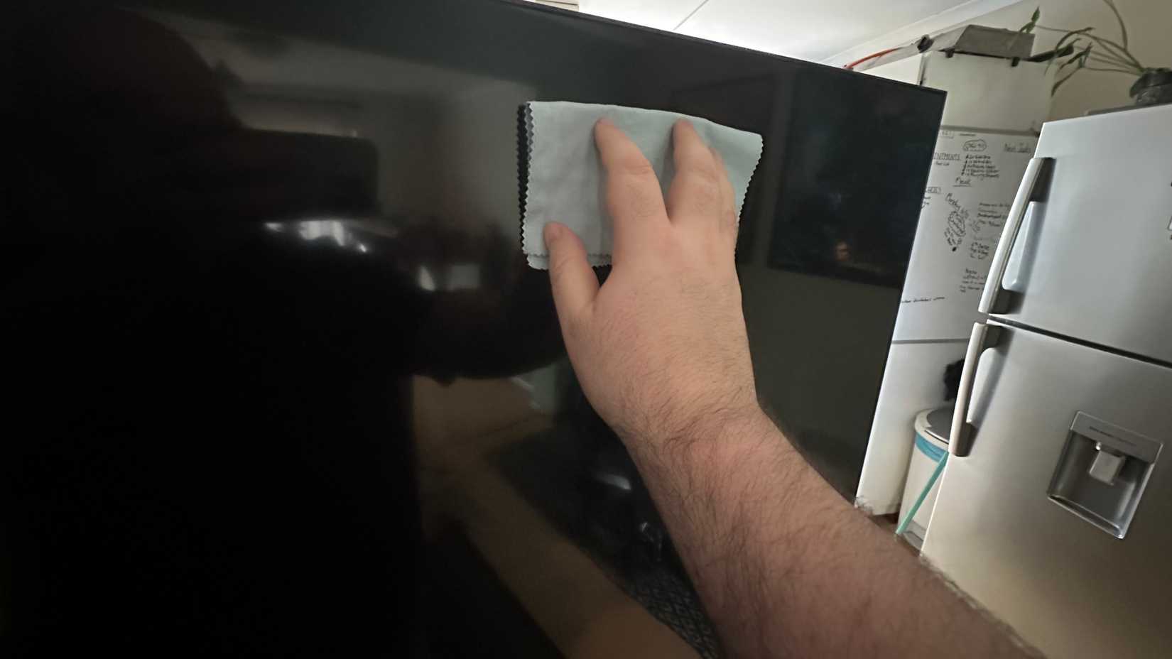 Wiping a TV down with a clean microfober cloth.