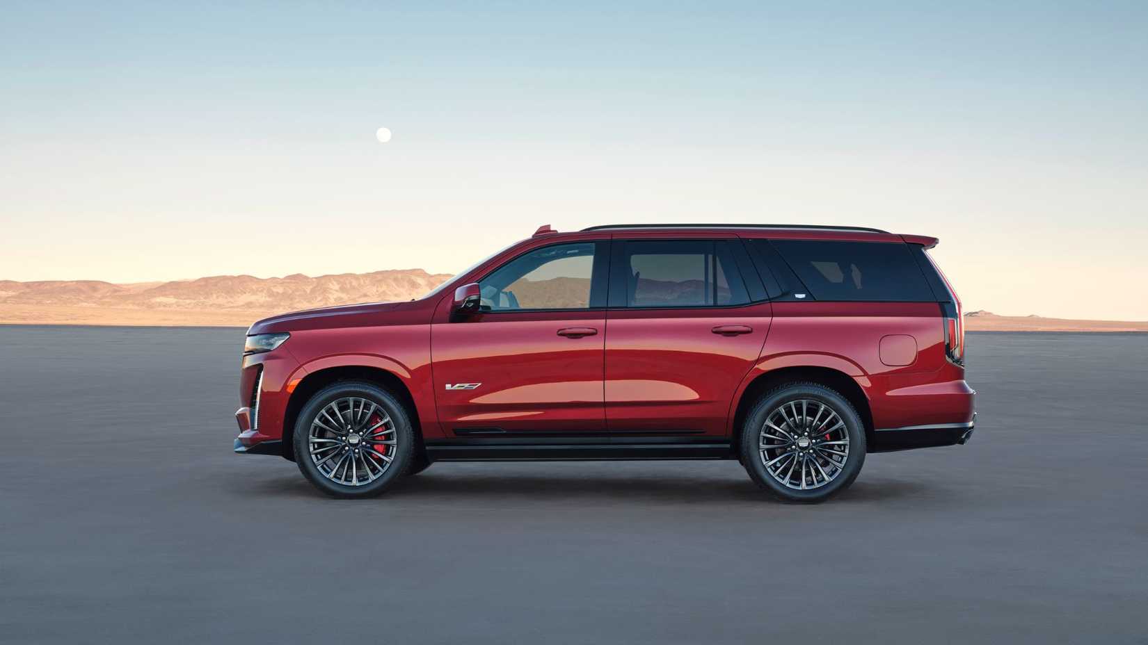 Foto estática do perfil lateral de um Cadillac Escalade-V 2023 vermelho.