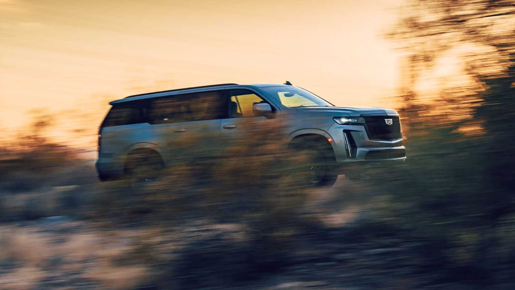Foto frontal dinâmica 3/4 de um Cadillac Escalade-V 2023 prateado.