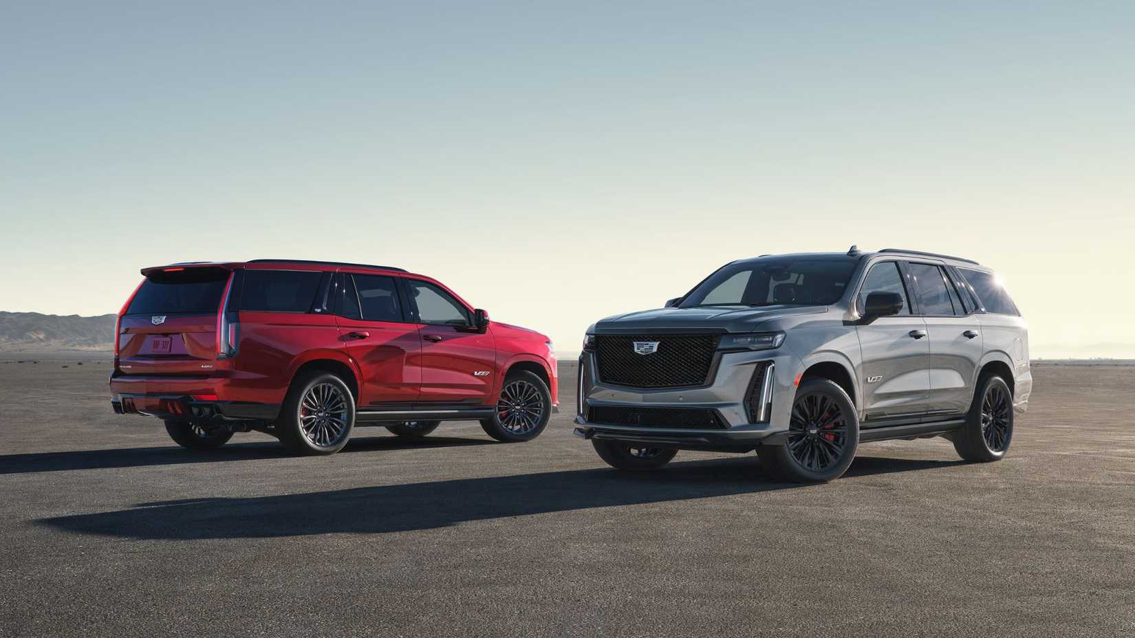 Vista traseira 7/8 do 2024 Cadillac Escalade V-Series em Radiant Red Metallic e vista frontal 7/8 do 2024 Escalade V-Series em Argent Silver Metallic.