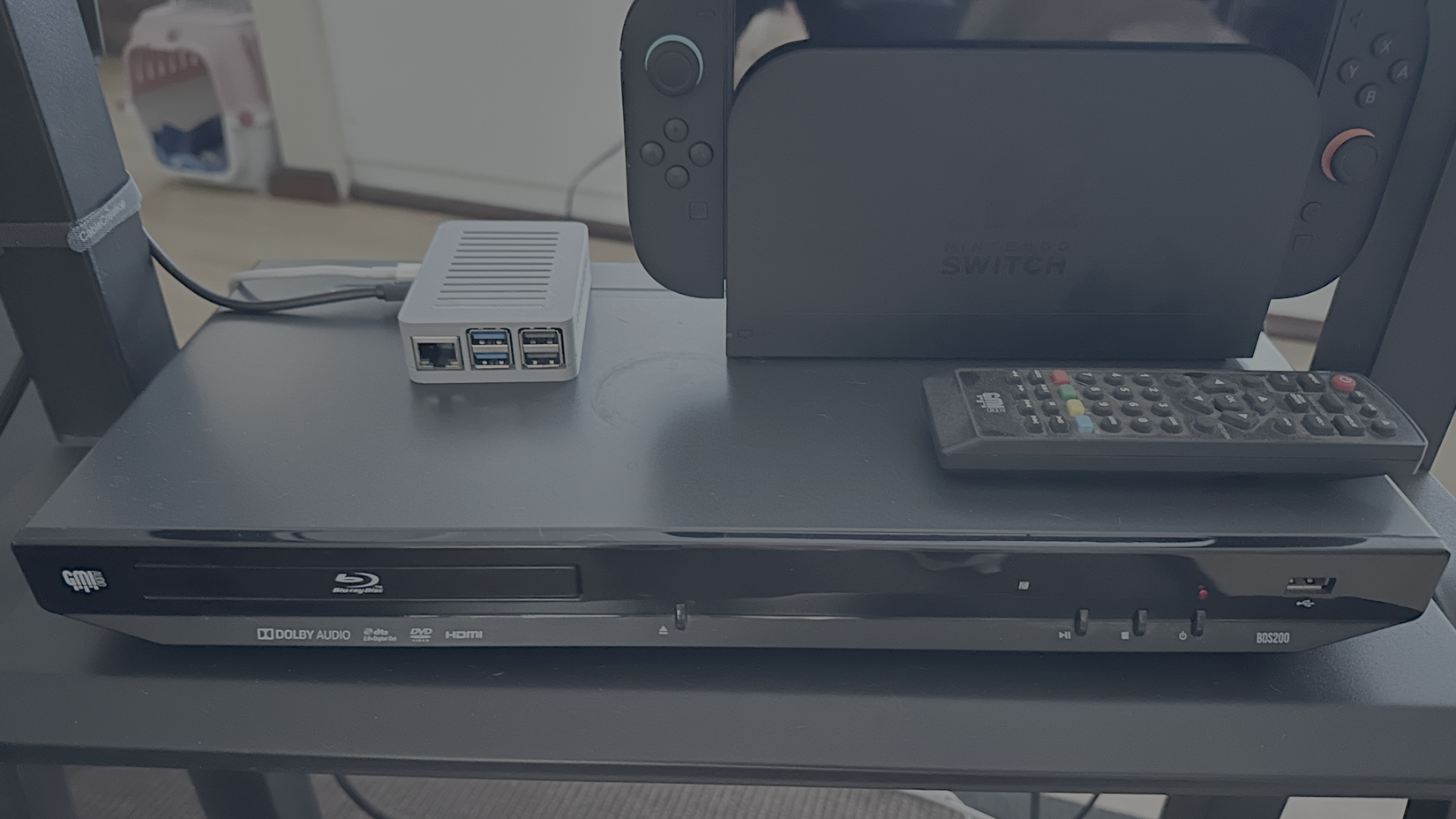 Una Rapsberry Pi en un soporte audiovisual junto a una Switch 2 y encima de un reproductor de Blu-Ray.
