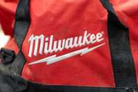 The Milwaukee logo embroidered in white on a red tool bag.