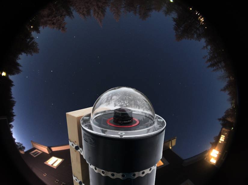 An AllSky camera setup with the sky and a house in the background.