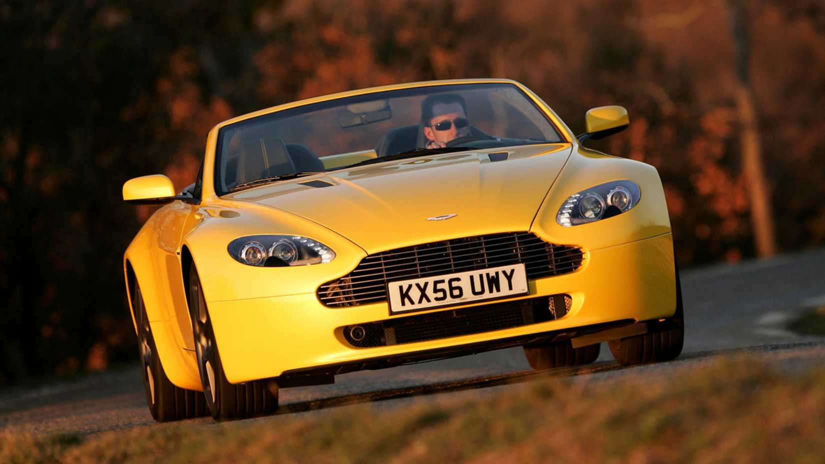 Dynamic shot of the front of a yellow 2007 Aston Martin V8 Vantage Roadster.