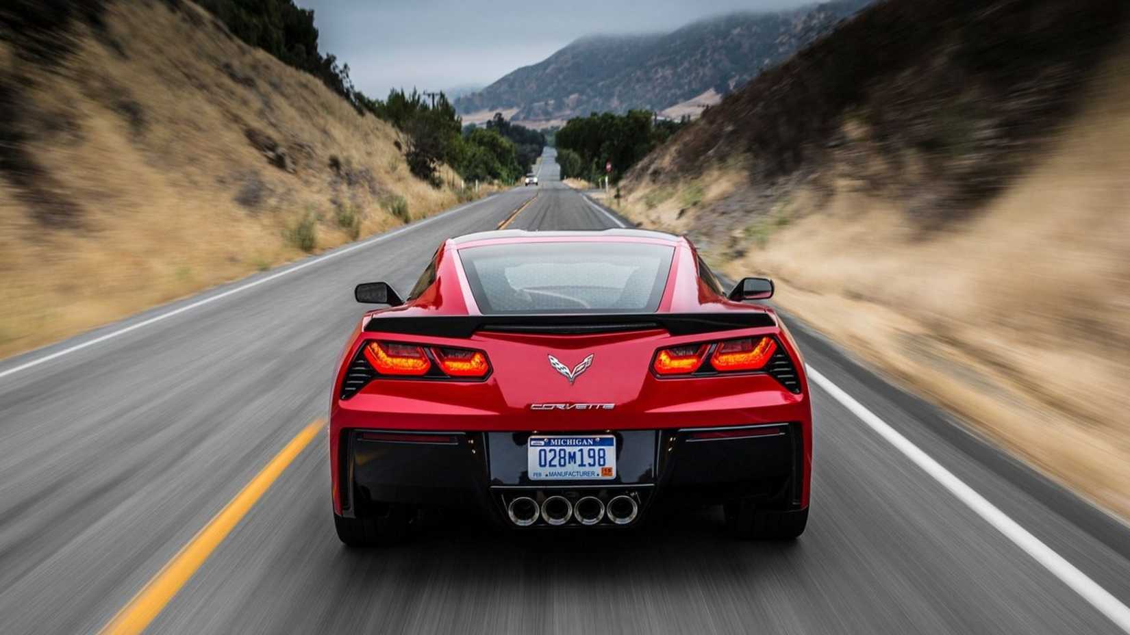 Dynamic rear-end shot of a red 2014 Chevrolet Corvette C7 Stingray driving on a country road.