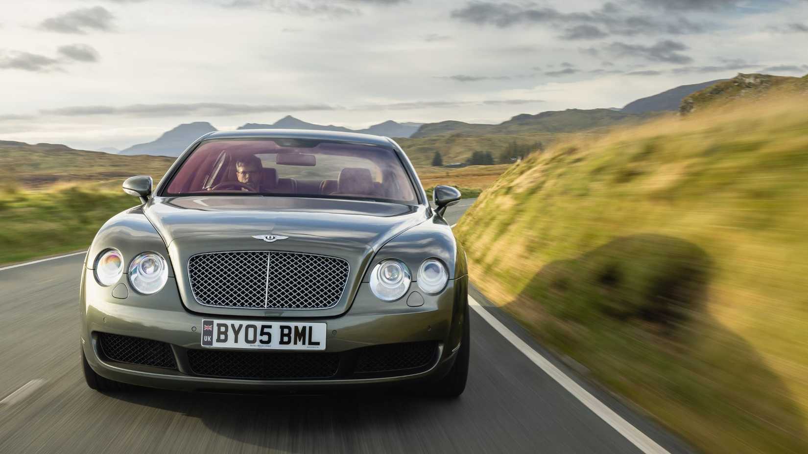 Dynamic shot of the front of a 2005 Bentley Continental Flying Spur driving down a country road.