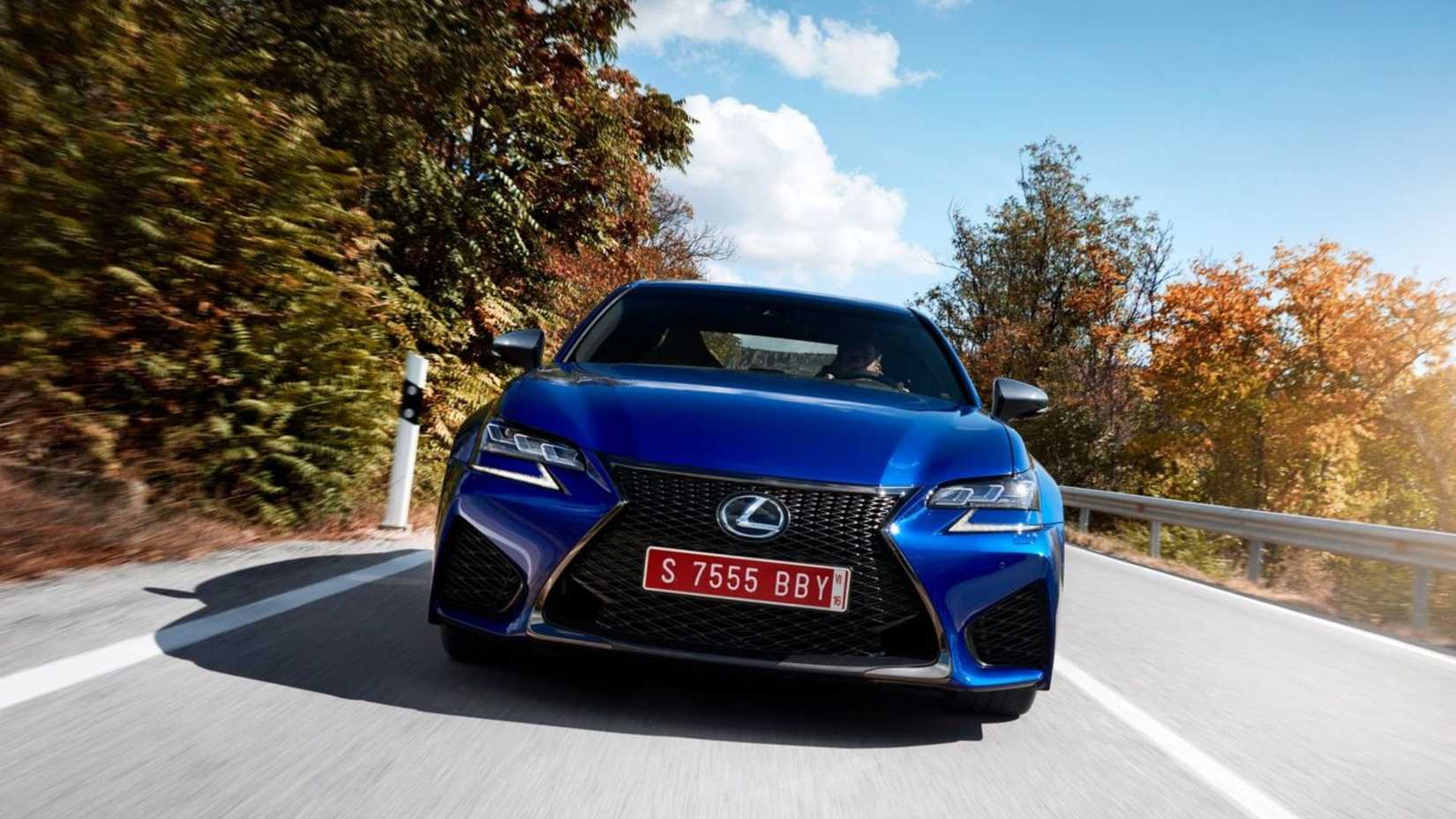 Toma dinámica del frente de un Lexus GS F 2016 azul conduciendo por una carretera rural.
