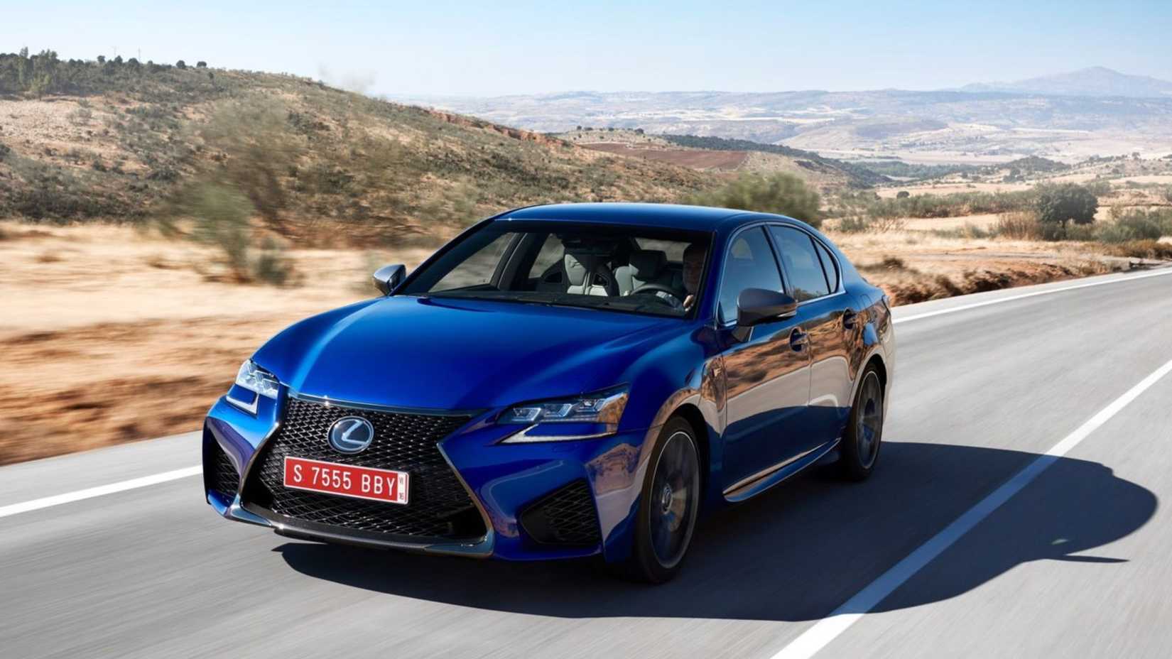 Toma dinámica de 3/4 del frente de un Lexus GS F 2016 azul conduciendo por una carretera rural.