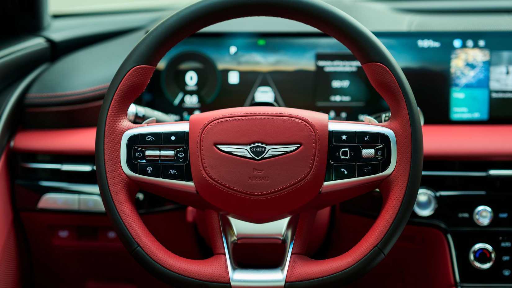 Close-up of the black and red leather steering wheel of the 2025 Genesis G80.
