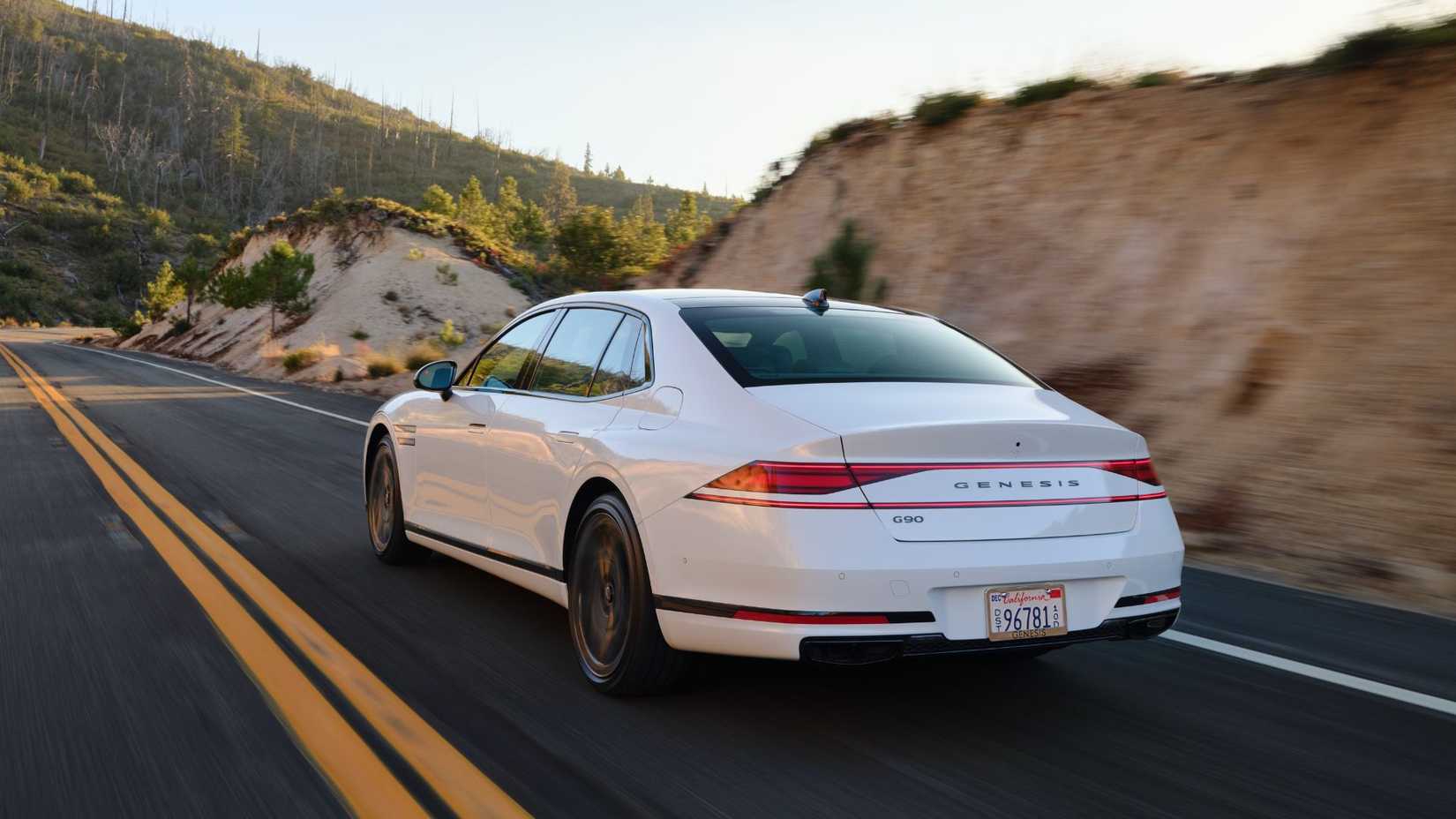 Dynamic rear 3/4 shot of a white 2026 Genesis G90 Prestige Black.