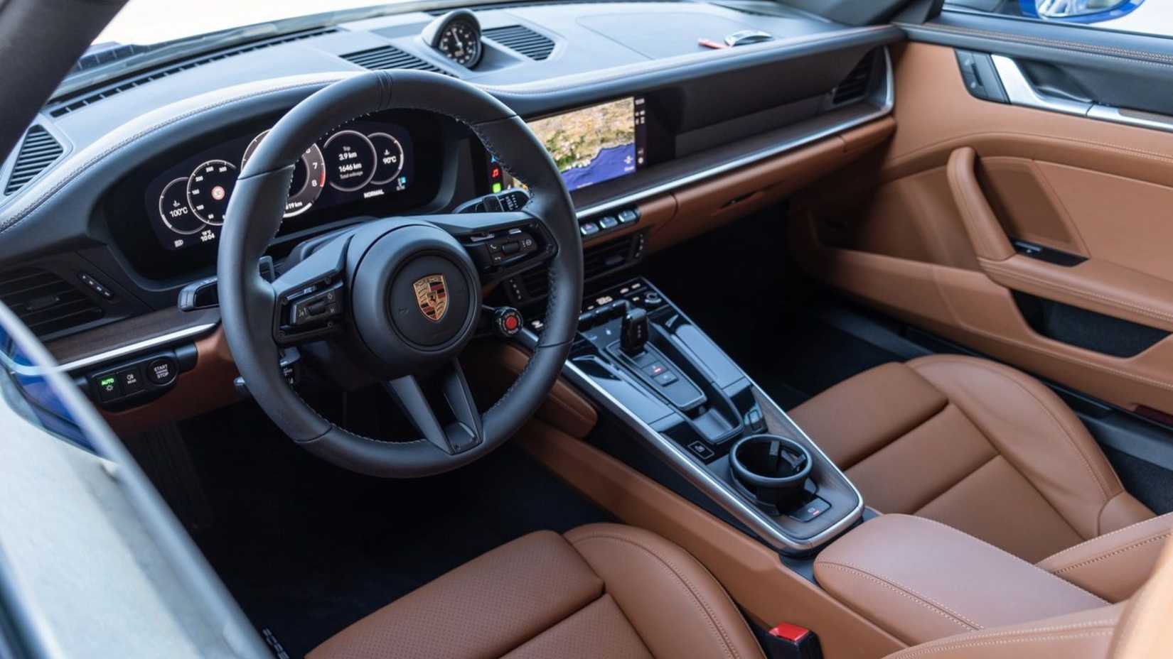 Shot inside the cabin of a 2025 Porsche 911 Carrera showing the tan leather interior and dashboard.