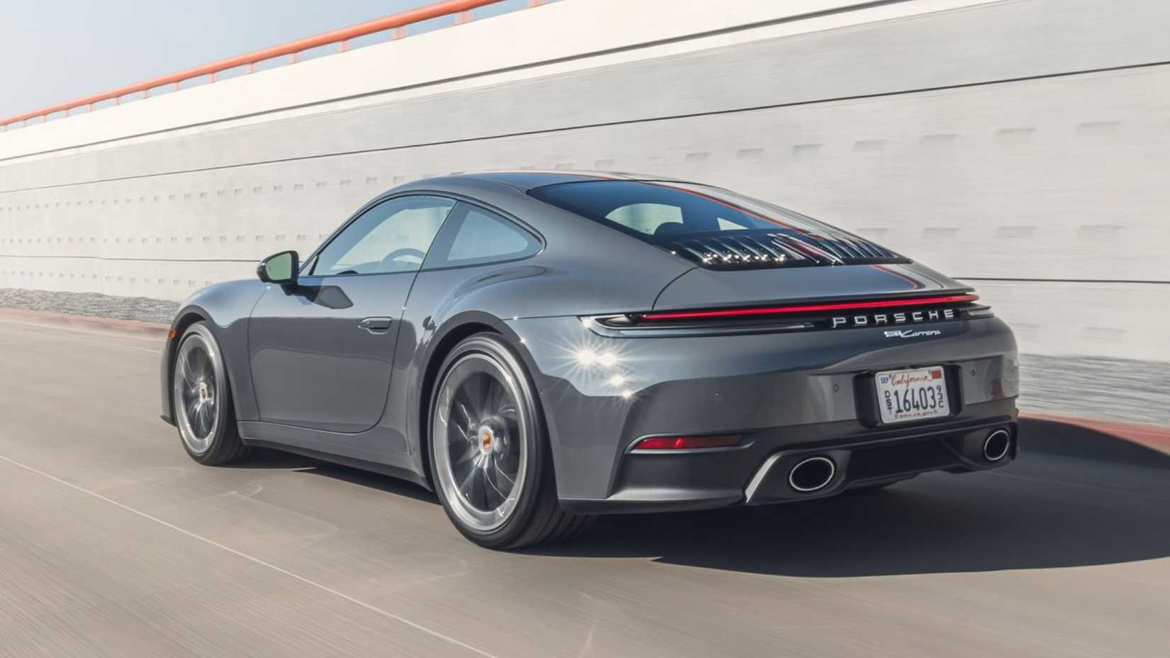 Dynamic rear 3/4 shot of a gray 2025 Porsche 911 Carrera.