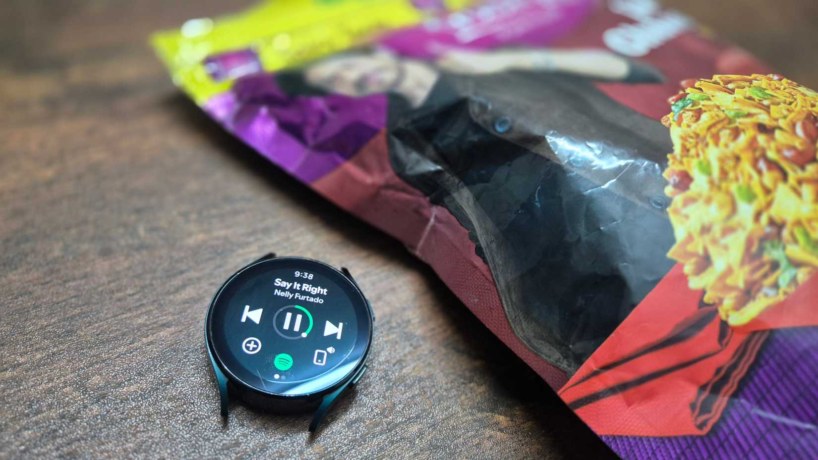 Samsung Galaxy Watch 4 відтворює музику на Spotify із пакетом із закусками збоку.