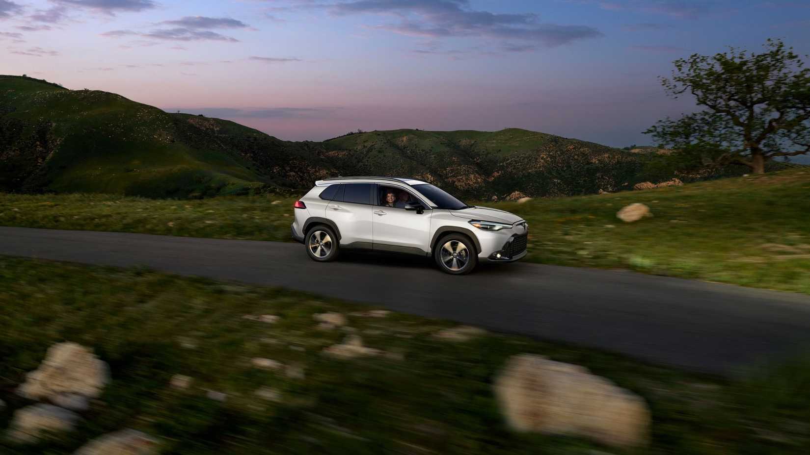 Dynamic side profile photo of a white 2025 Toyota Corolla Cross Hybrid XSE.