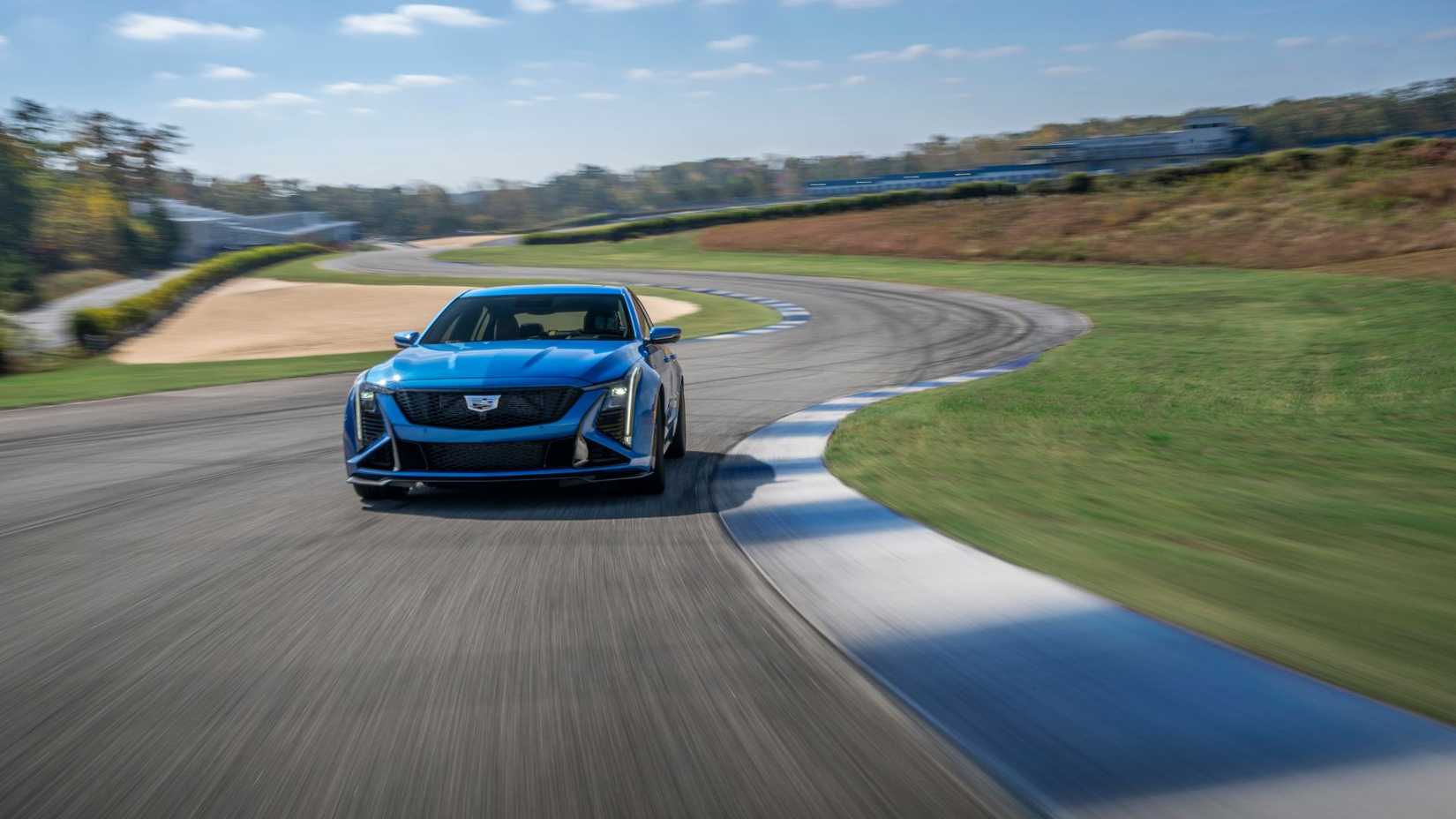 Dynamic front-end shot of a blue 2026 Cadillac CT5-V Blackwing on a racetrack.