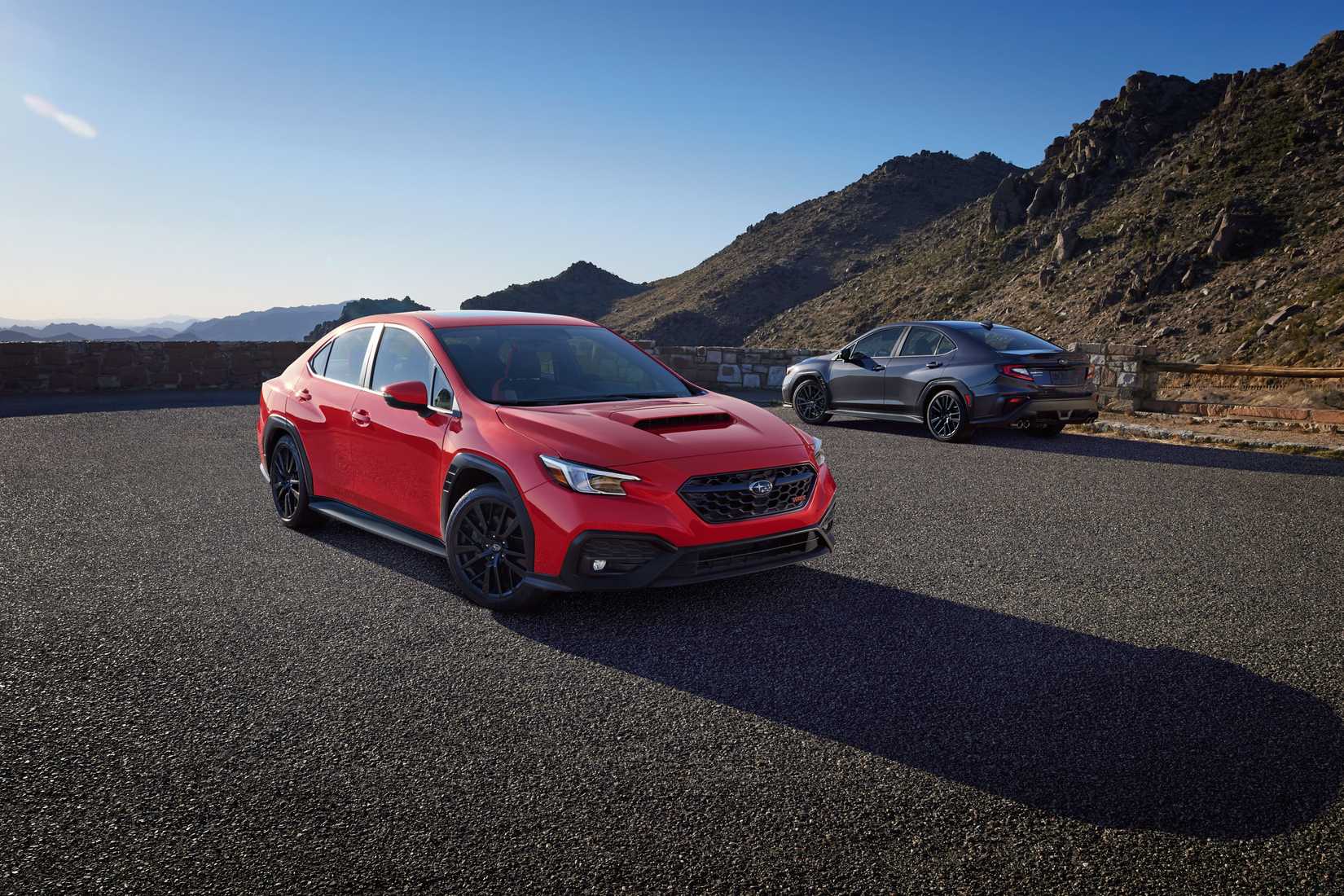 Two 2026 Subaru WRX models parked side-by-side, one is red and the other is gray. The gray one is farther away in the background.
