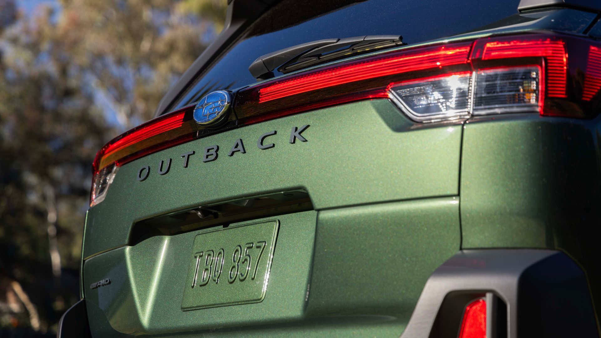 Close-up of the badge on the rear hatch of a green 2026 Subaru Outback.