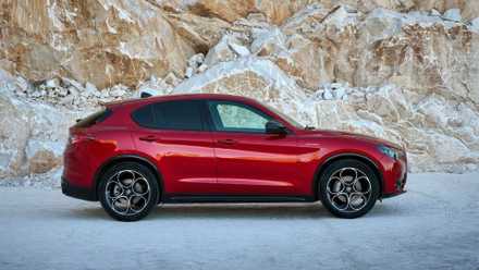 Static side profile shot of a red 2023 Alfa Romeo Stelvio.
