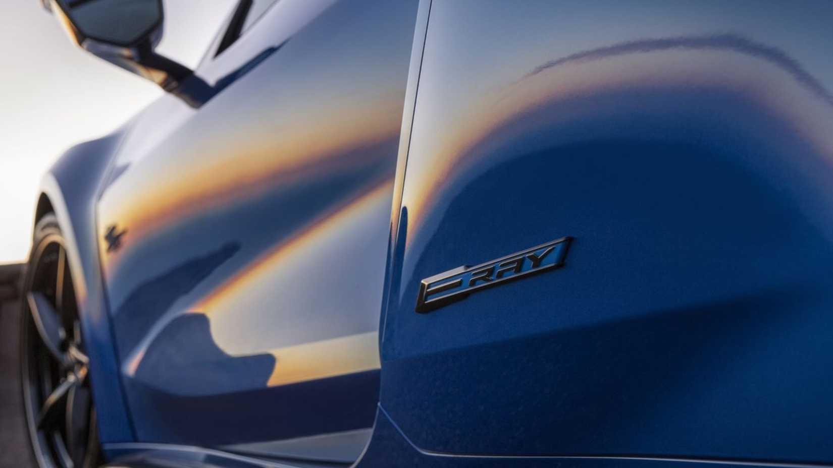 Gros plan de l'insigne sur les 3/4 arrière d'une Chevrolet Corvette E-Ray 2024 bleue.