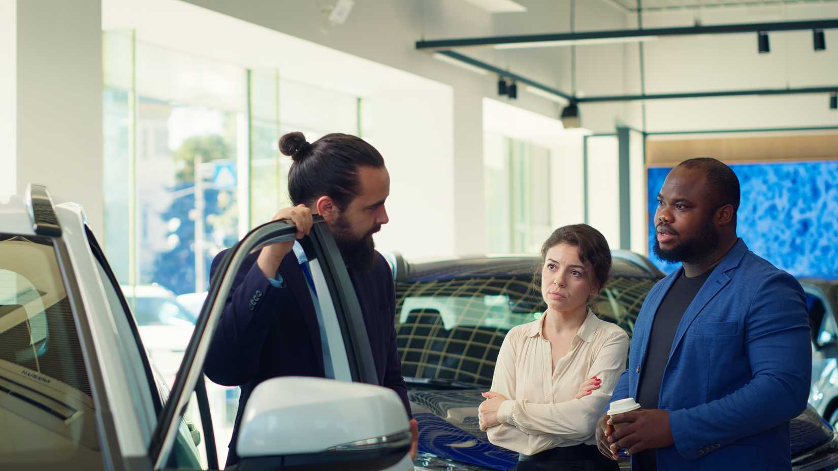 Dealership sales staff member talking with a with family on the showfloor.