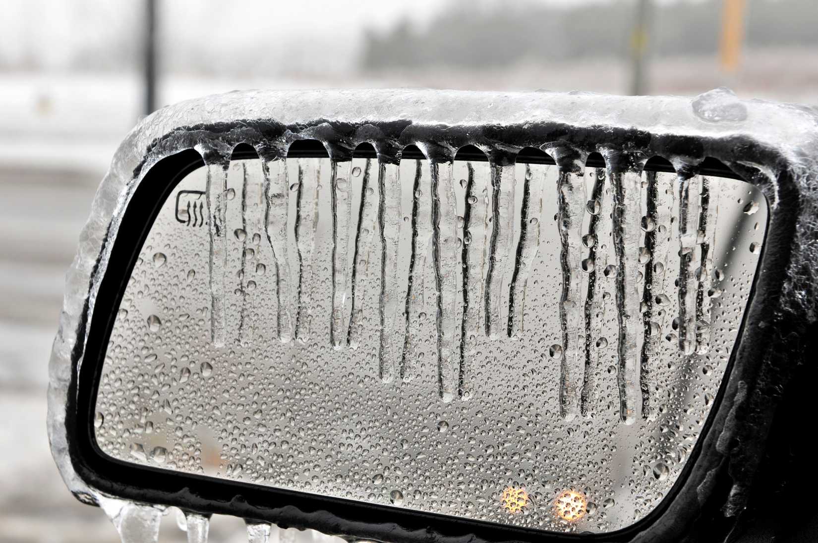 A photo of a drivers side car mirror covered in ice and condensation.