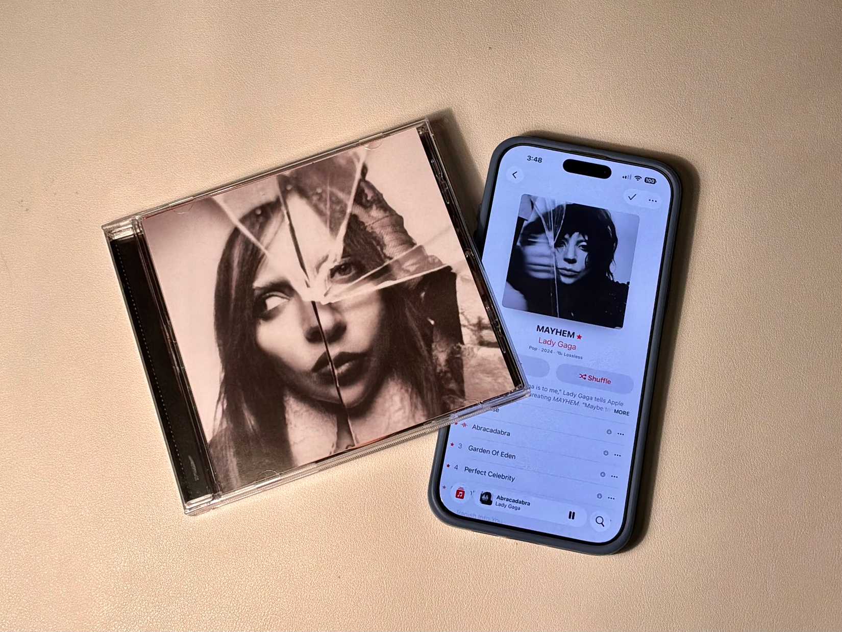 CD next to an iPhone with Apple Music open, showcasing different album art for the album: Chromatica.