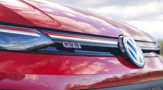 Close-up shot of the GTI badging on the grille of a red 2025 Volkswagen Golf GTI Autobahn.