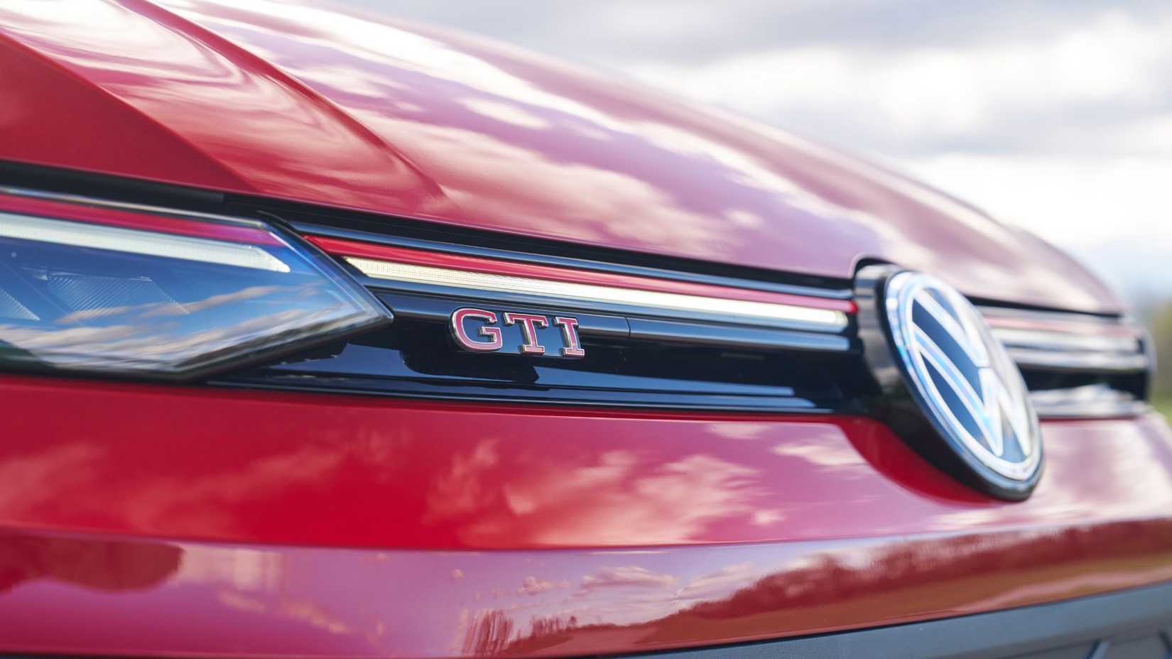 Close-up shot of the GTI badging on the grille of a red 2025 Volkswagen Golf GTI Autobahn.