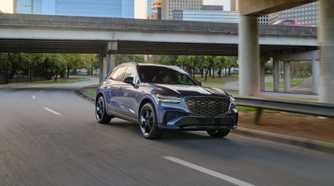 Dynamic front 3/4 shot of a gray 2026 Genesis GV70.