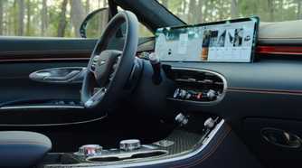 Close-up shot of the steering wheel and infotainment screen inside the cabin of a 2026 Genesis GV70.