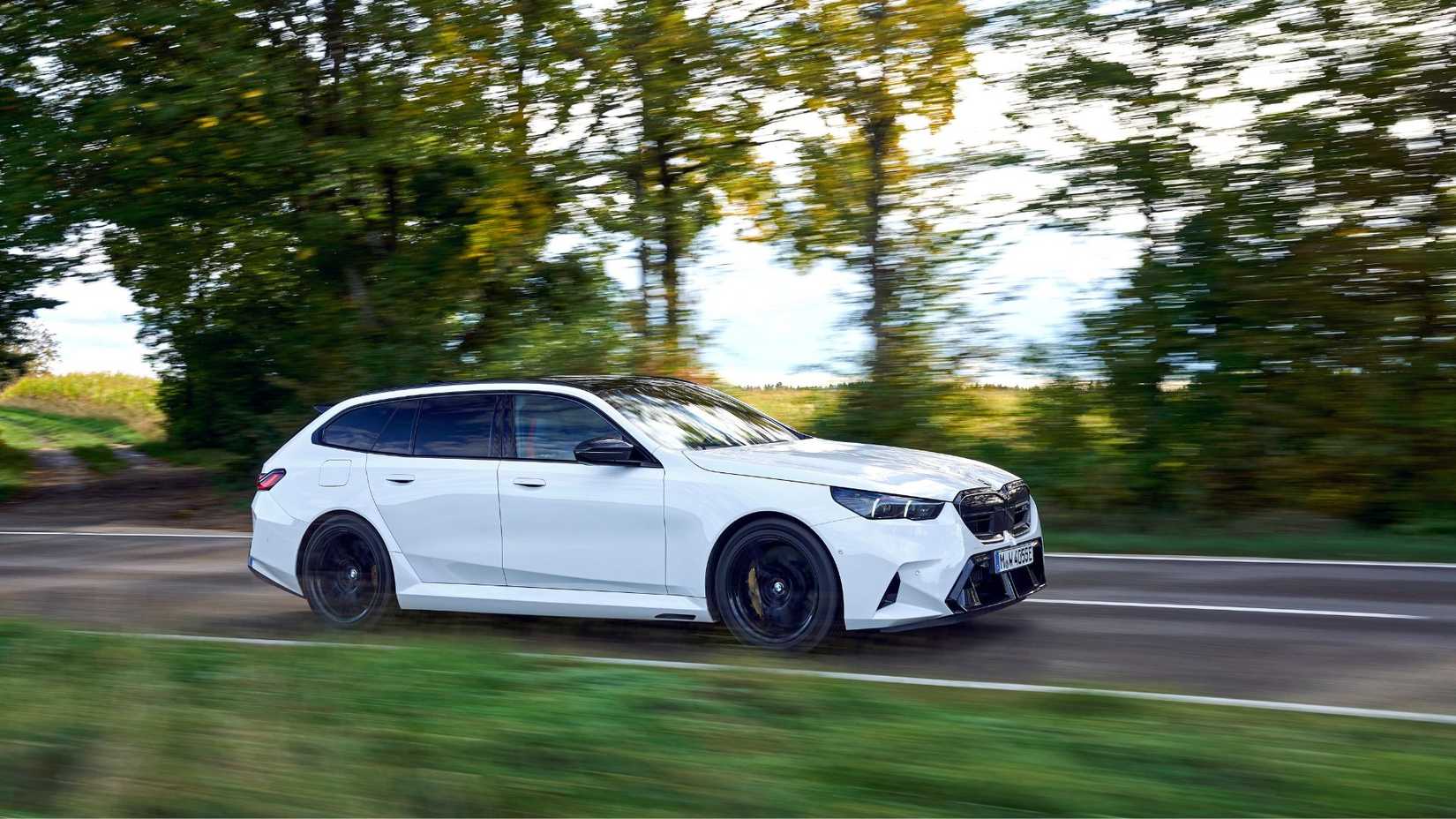 Dynamic side profile shot of a white BMW M5 Touring.
